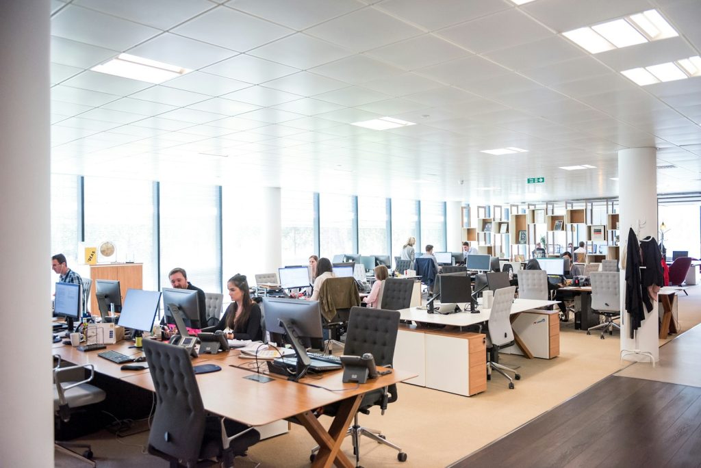 Open space lumineux où plusieurs collègues travaillent à leur bureau, illustrant l'environnement de bureau propice à la circulation des virus en hiver.