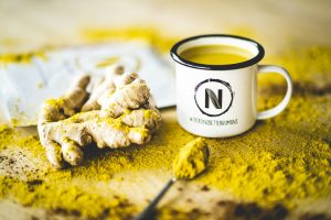Tasse de tisane chaude à côté d'une pile de poudre de curcuma